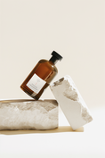 Load image into Gallery viewer, Festive Cranberry diffuser bottle resting on a pale stone plinth beside a stone slab
