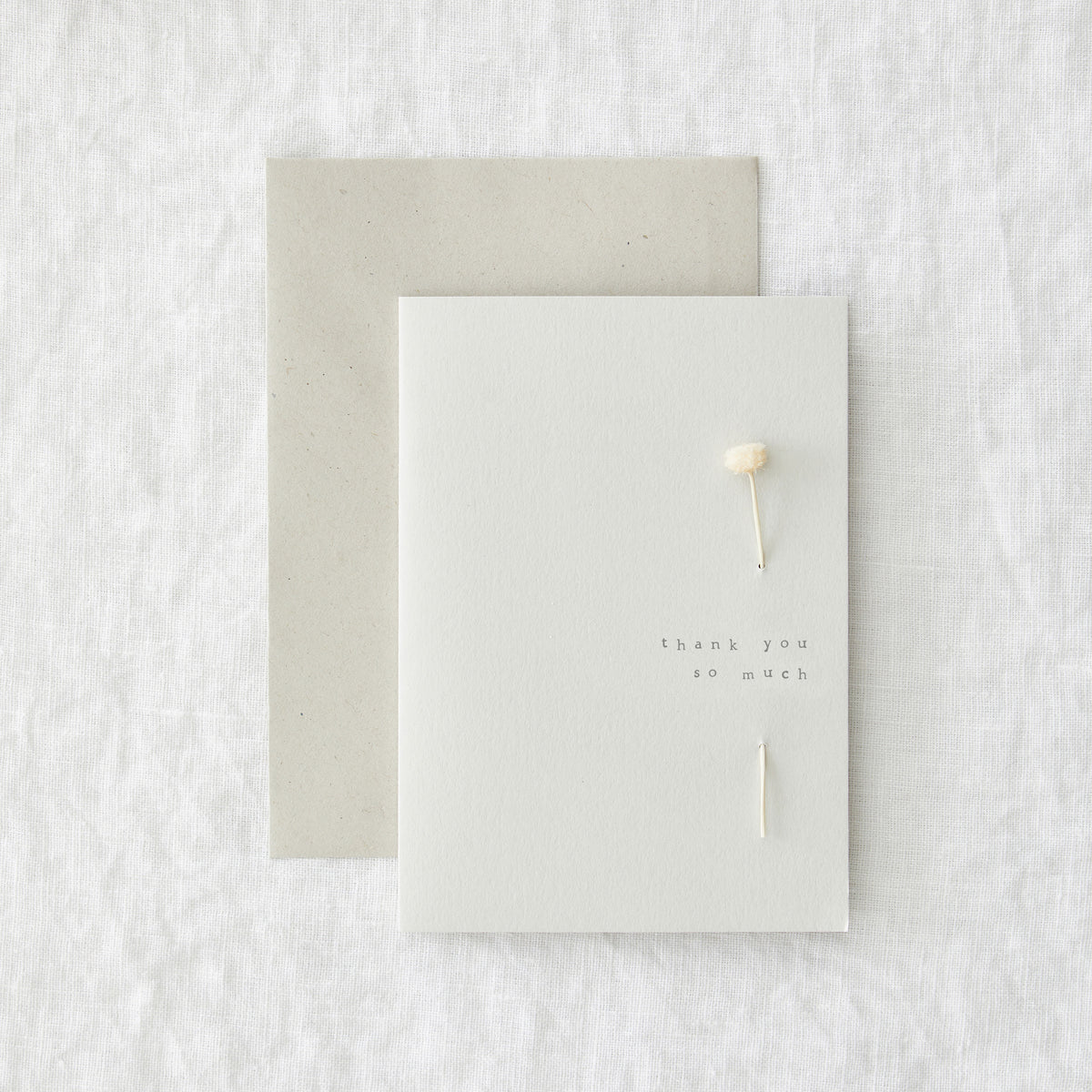 Thank you card in speckled cream paper reading 'thank you so much', shown with its envelope