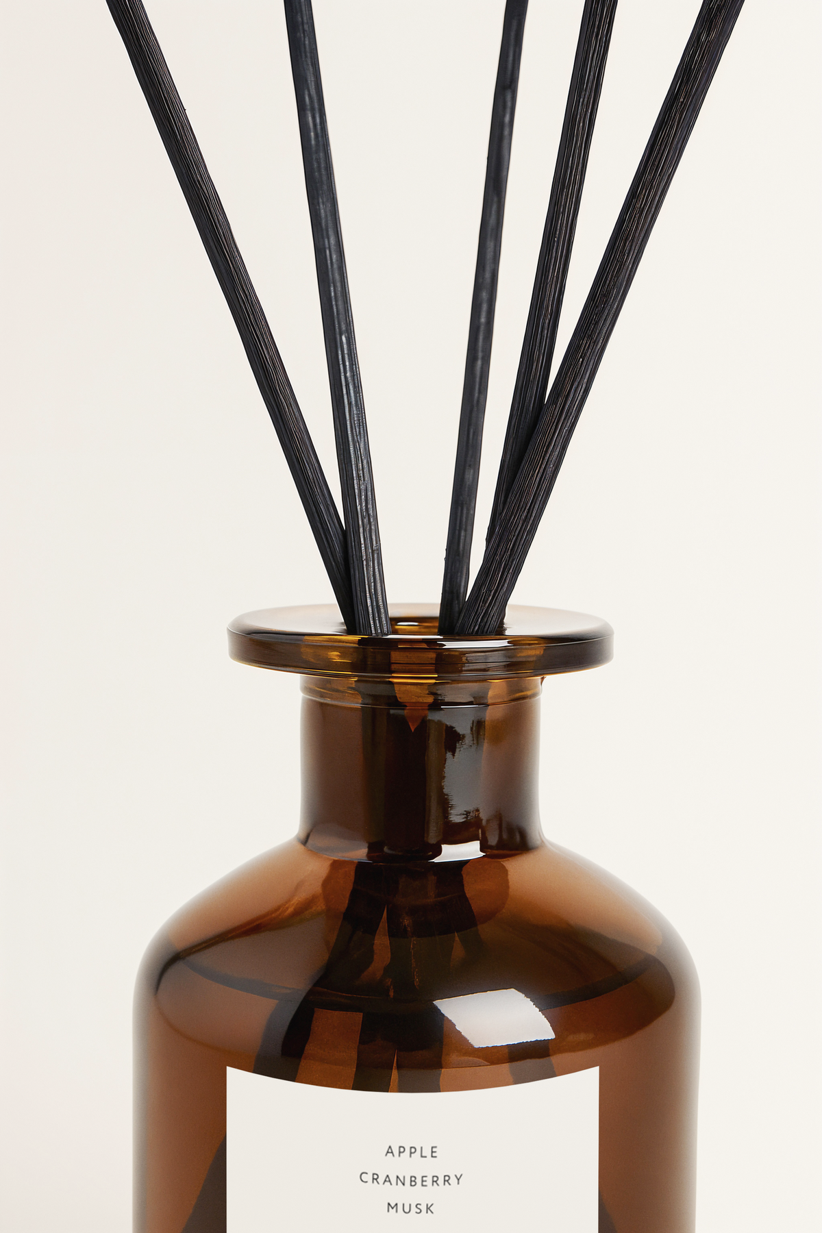 Festive Cranberry reed diffuser in amber glass with a full fan of black reeds