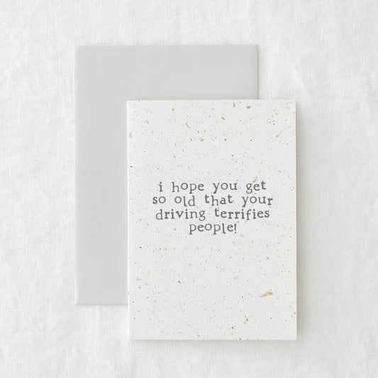 Birthday card in speckled cream paper reading 'I hope you get so old that your driving terrifies people', shown with its envelope