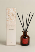 Load image into Gallery viewer, Christmas Spice 95ml reed diffuser in amber glass with black reeds, beside its printed Little London Gifts Co gift box
