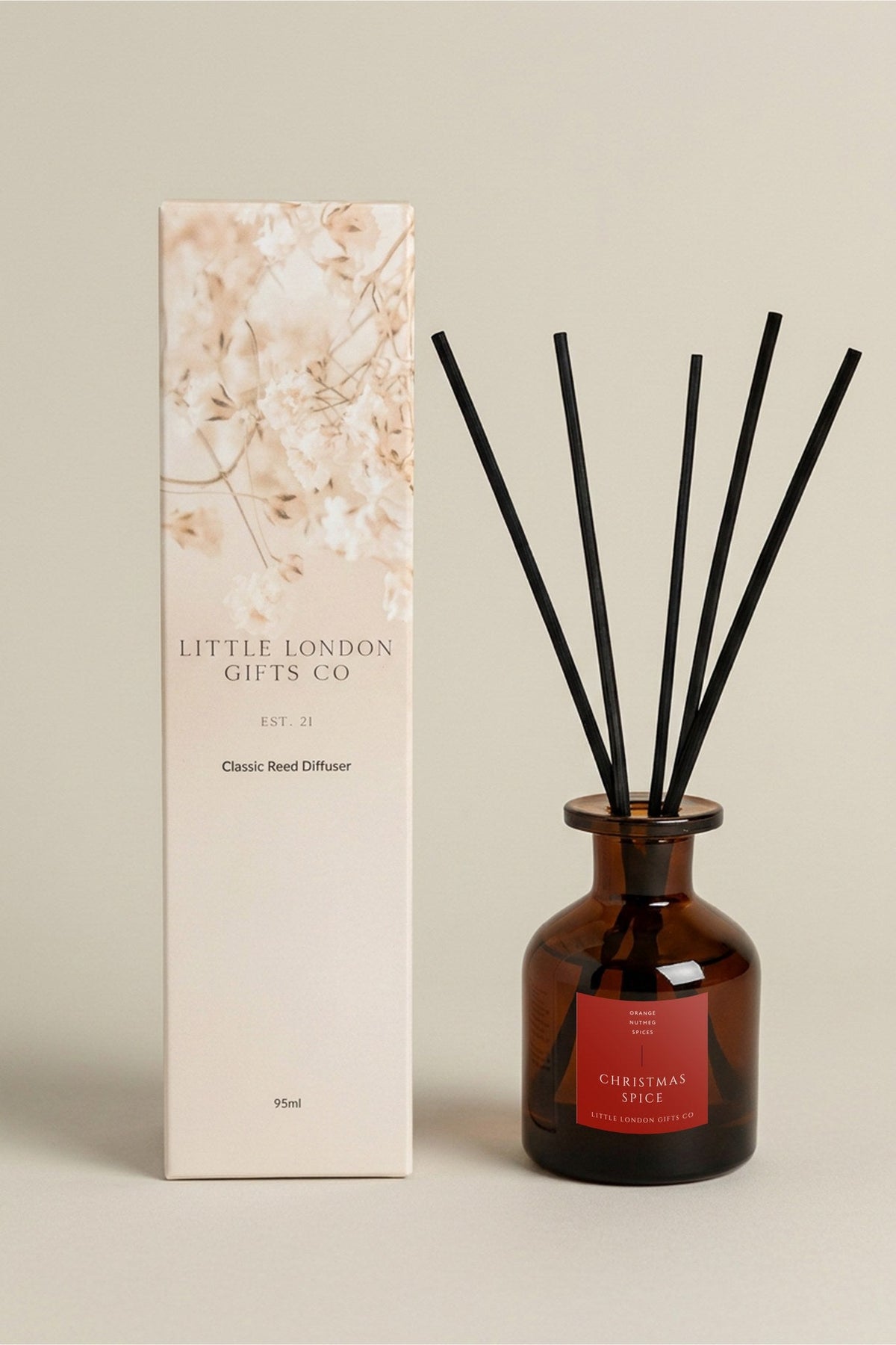 Christmas Spice 95ml reed diffuser in amber glass with black reeds, beside its printed Little London Gifts Co gift box