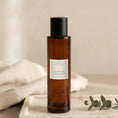 Load image into Gallery viewer, Citrus & Bergamot room spray 100ml, amber glass bottle on a marble tray with linen and eucalyptus
