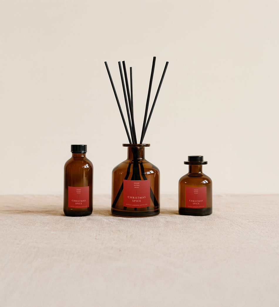 Christmas Spice reed diffusers in three sizes, amber glass with red labels and black reeds