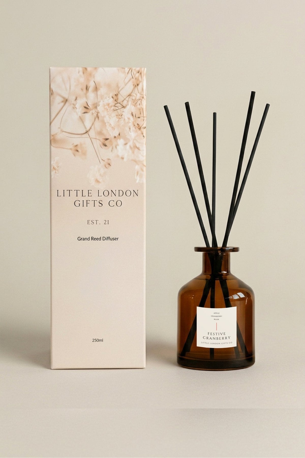 Festive Cranberry 250ml reed diffuser, large amber bottle with black reeds, beside its cream floral-print Little London Gifts Co gift box