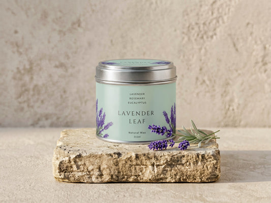Lavender Leaf candle tin in brushed silver with a sage green label printed with lavender, styled with fresh lavender stems on stone