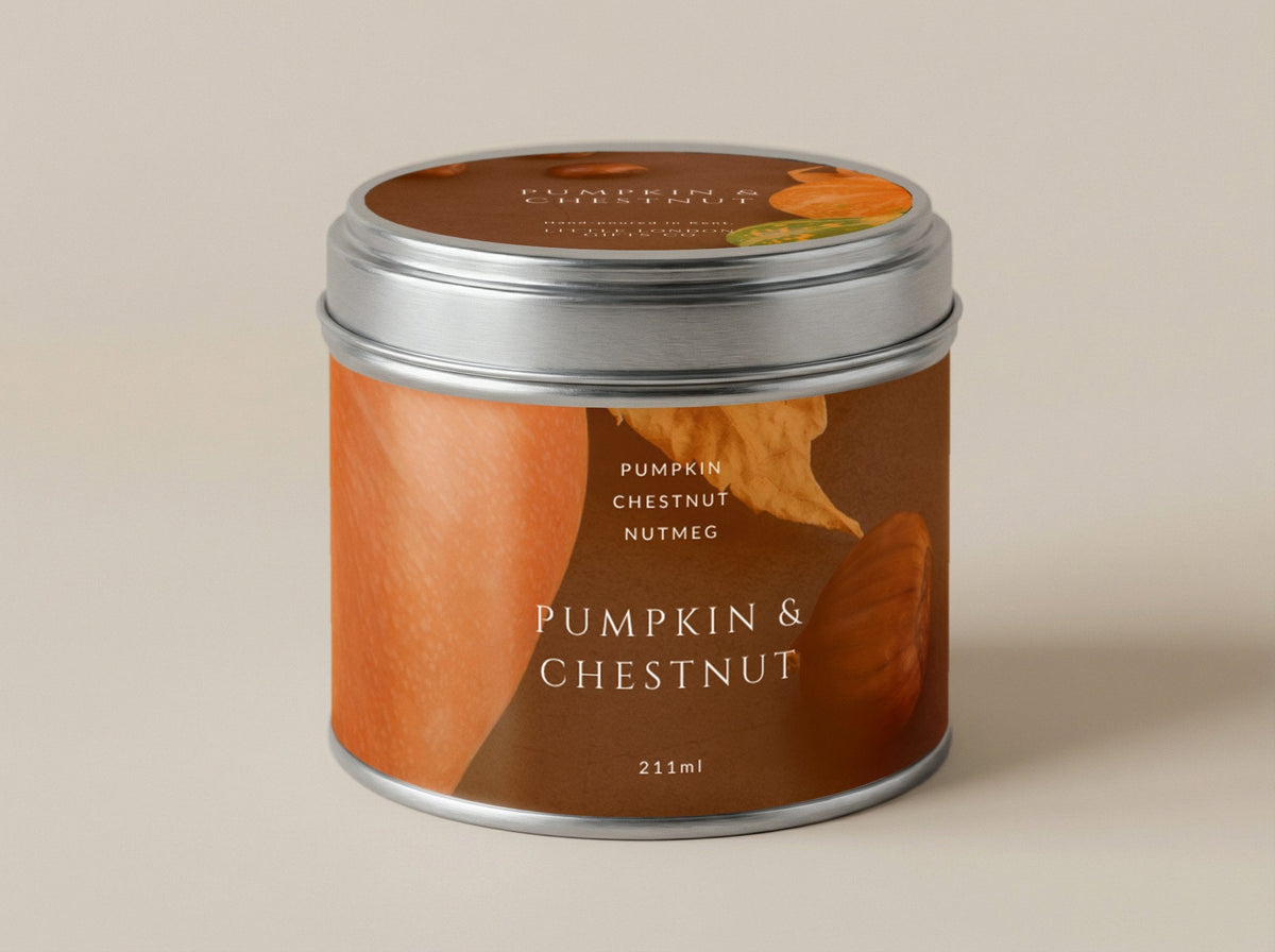 Pumpkin & Chestnut candle tin 211ml in orange and brown with autumn leaf artwork, silver lid on, on a plain warm backdrop