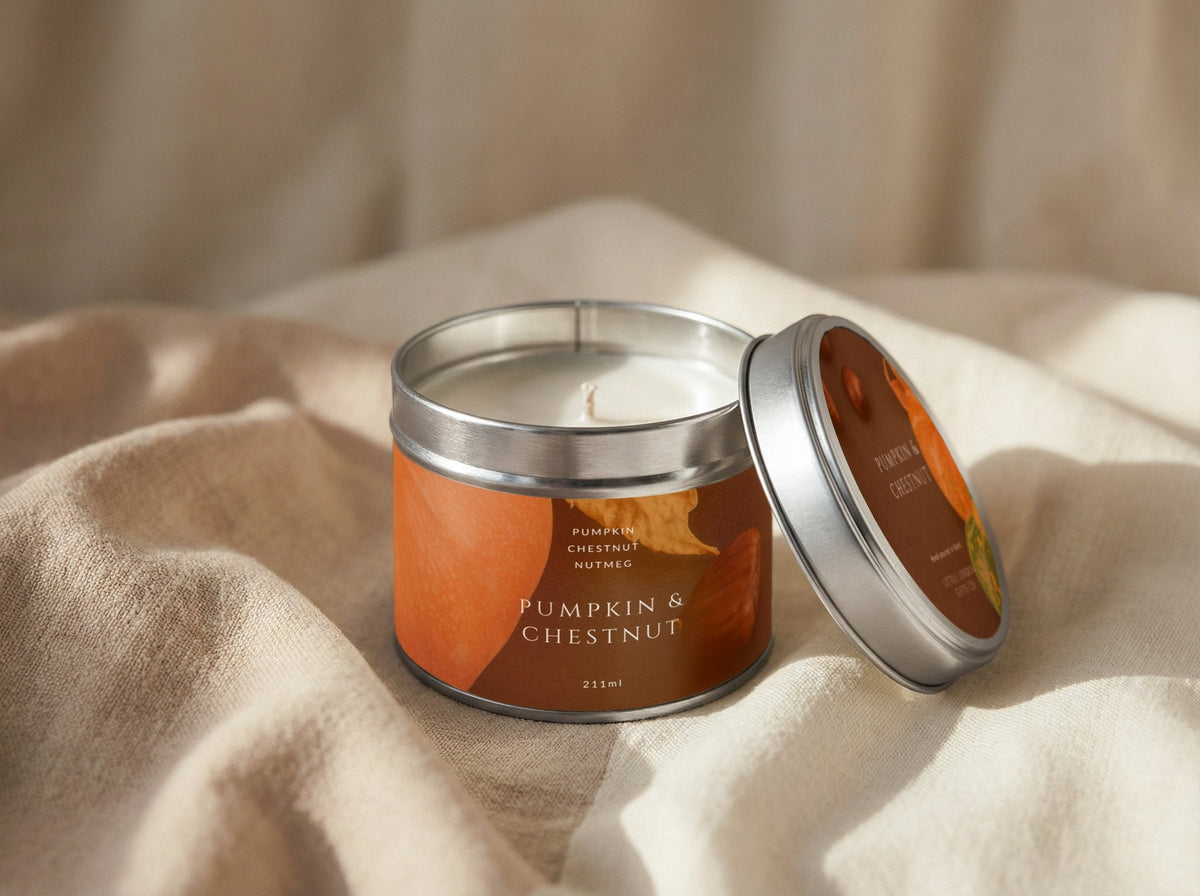 Pumpkin & Chestnut candle tin 211ml open on draped linen, silver lid propped to show the printed lid