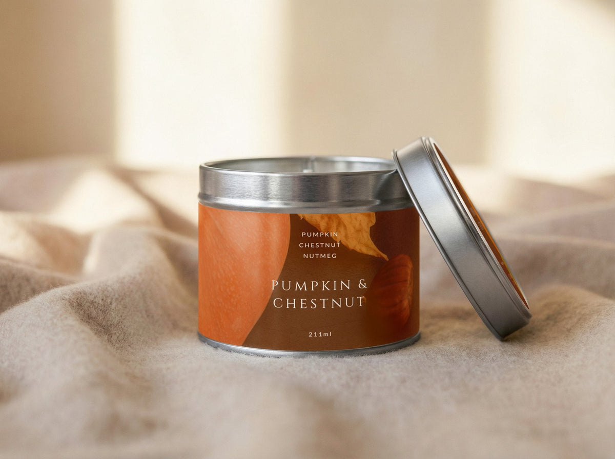 Pumpkin & Chestnut candle tin 211ml open with its silver lid propped, in warm side light on cream fabric