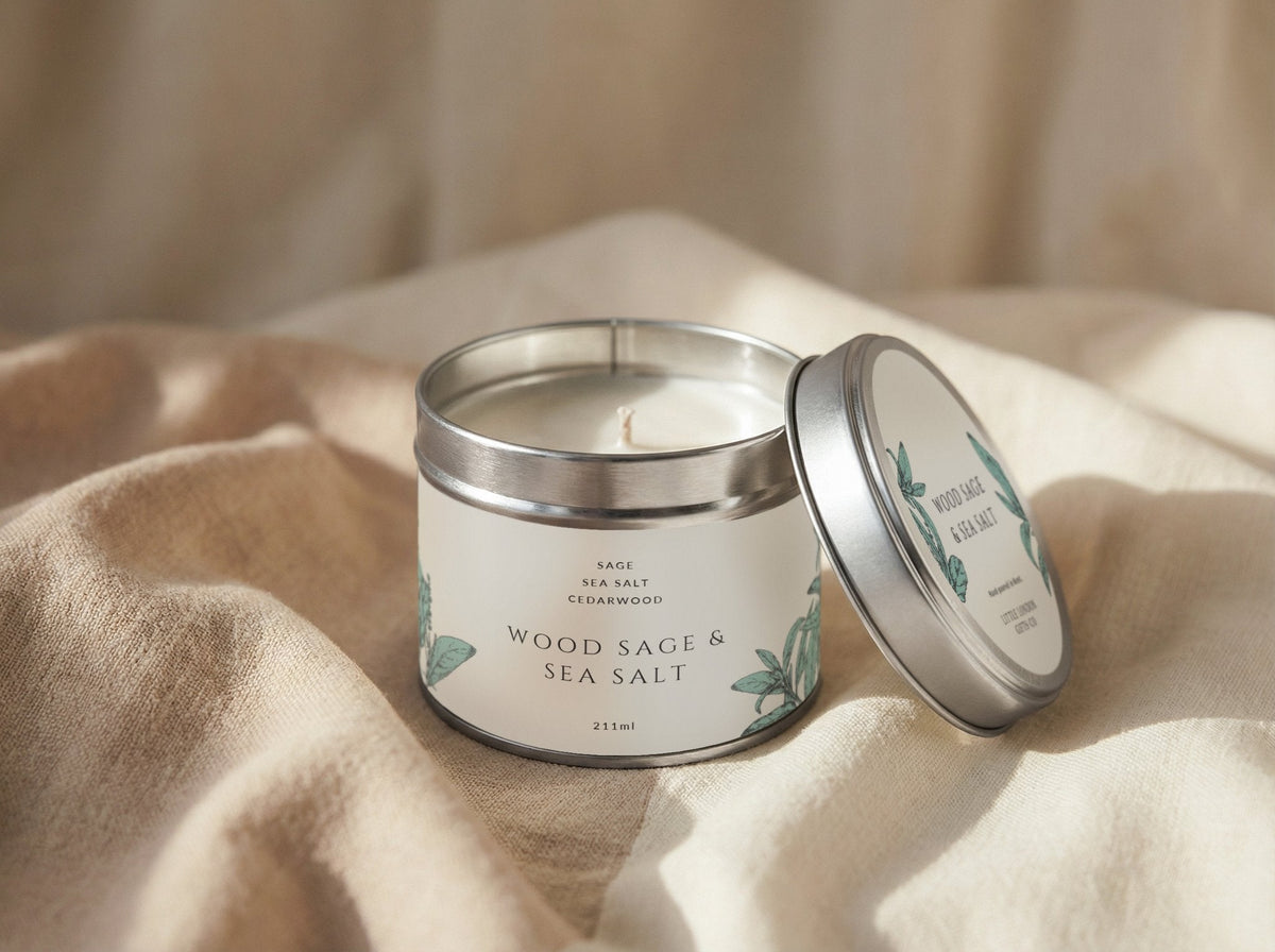 Sage & Sea Salt candle tin 211ml open on draped linen, silver lid propped to show the printed lid
