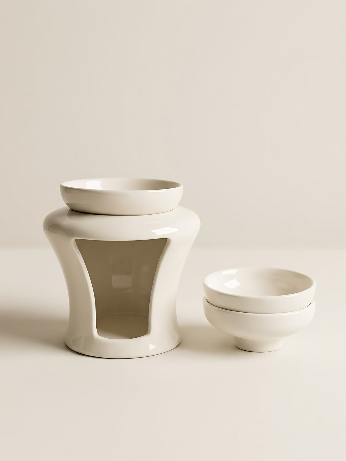 Close-up of the cream ceramic Vase Wax Burner with its arched tealight opening and two spare wax melt dishes