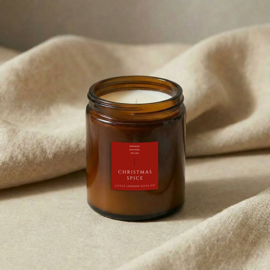 Christmas Spice candle in amber glass with the lid off, resting on a cream knitted throw
